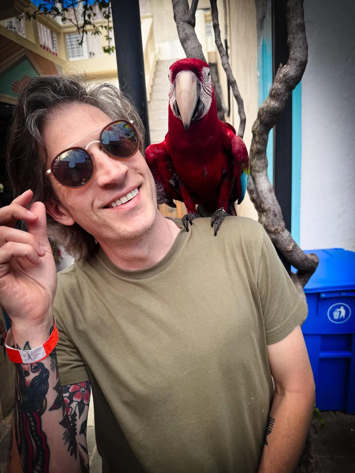 Jake Miller with a bright red parrot, showing the person and artist behind Pink Stack Studio.